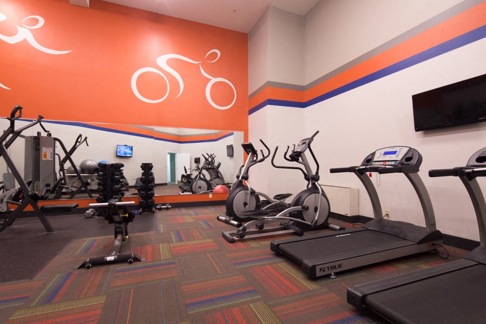 a gym with cardio machines and bikes in a room with a television