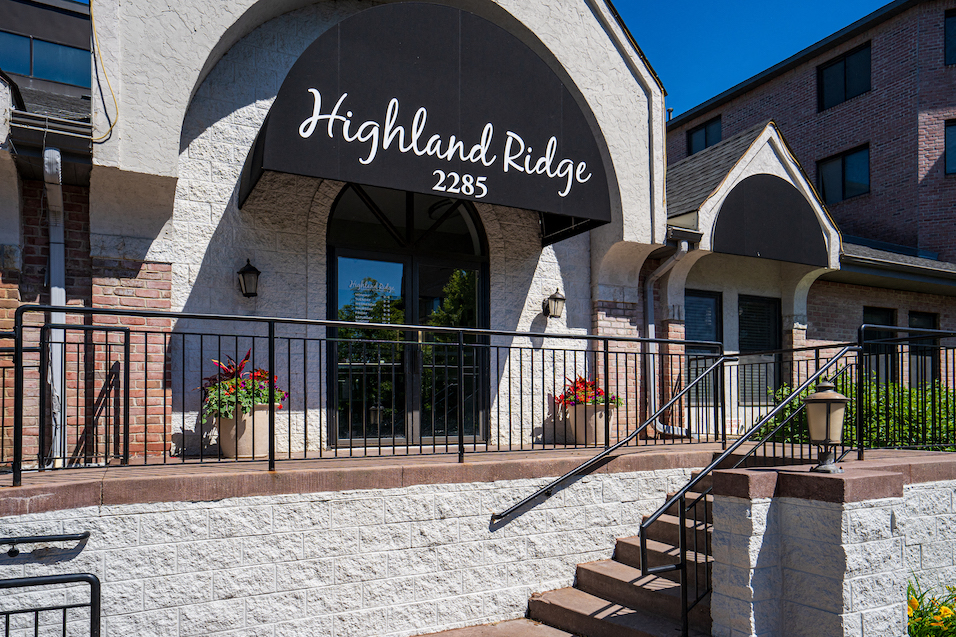Exterior shot with stairs leading to front door and a black awning with the words "Highland Ridge 2285" written in white