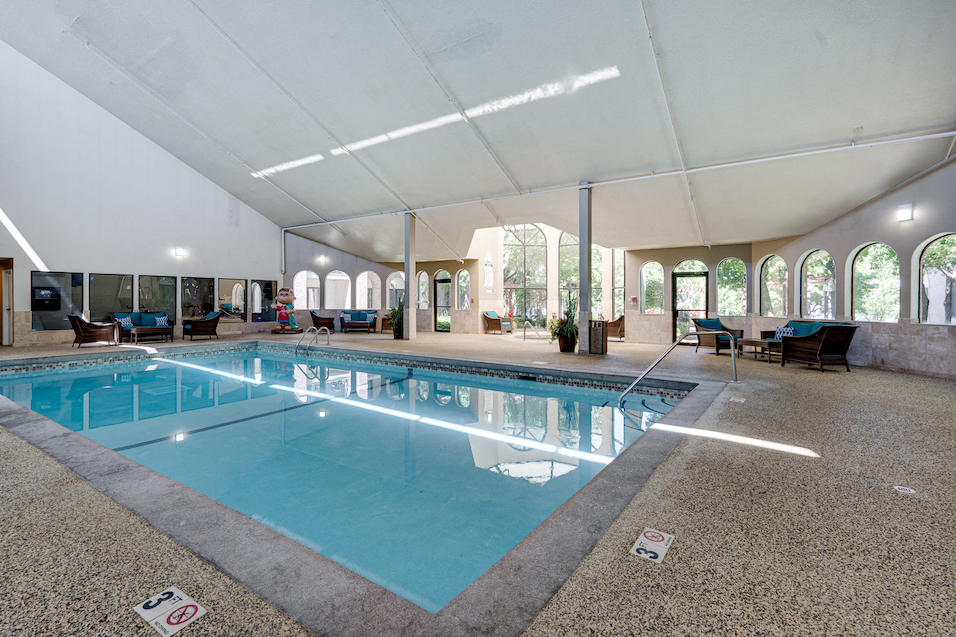 Indoor pool with high ceiling and patio seating