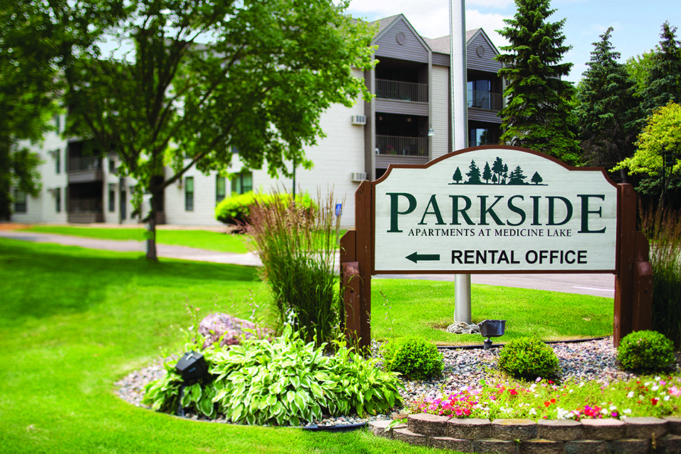 Sign that says "Parkside apartments at Medicine Lake" on it with the words "Rental Office" and a left arrow below it