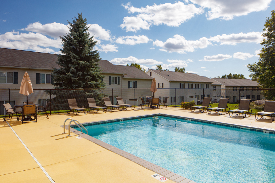 outdoor pool on a sunny day with multiple deck chairs