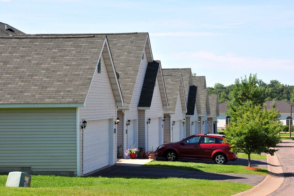 row of houses and garages with a red car parked in front of one