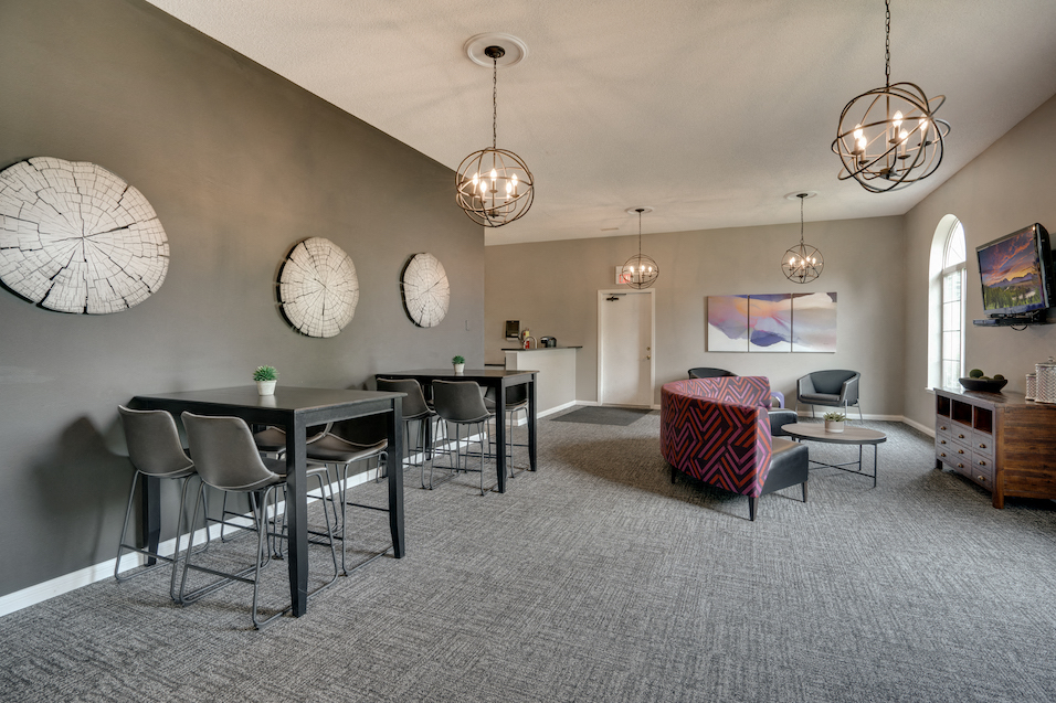 community room with tables and chairs, a couch, and a TV on the wall