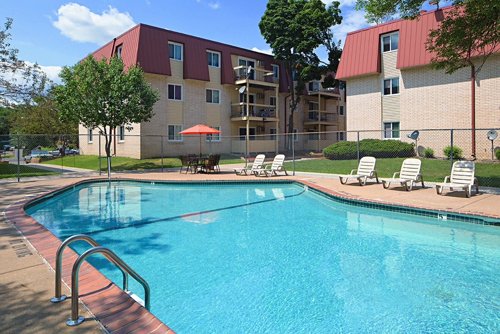 a swimming pool with chairs and a building in the background