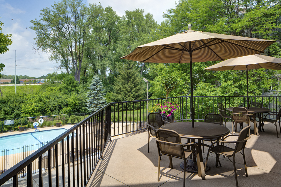 Sun deck with circular tables shielded by umbrellas overlooking a pool