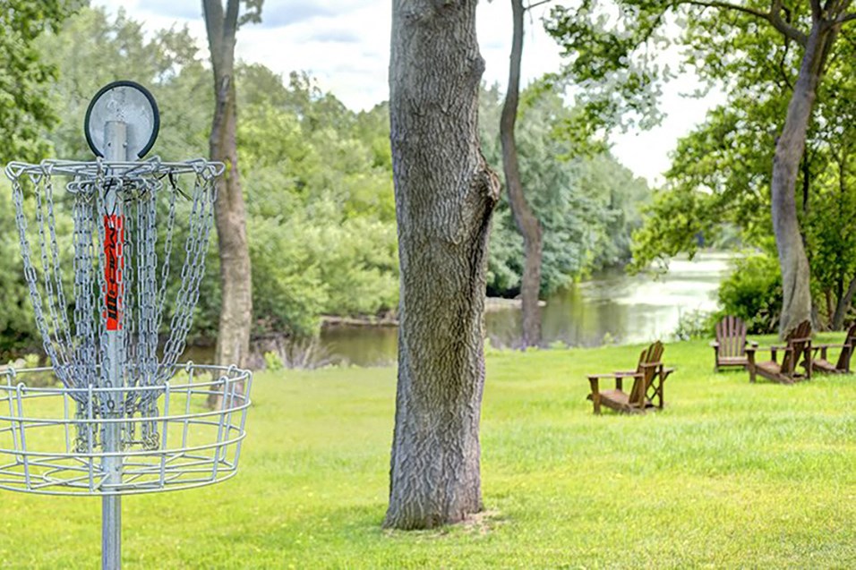 a frisbee catcher in the grass next to a tree