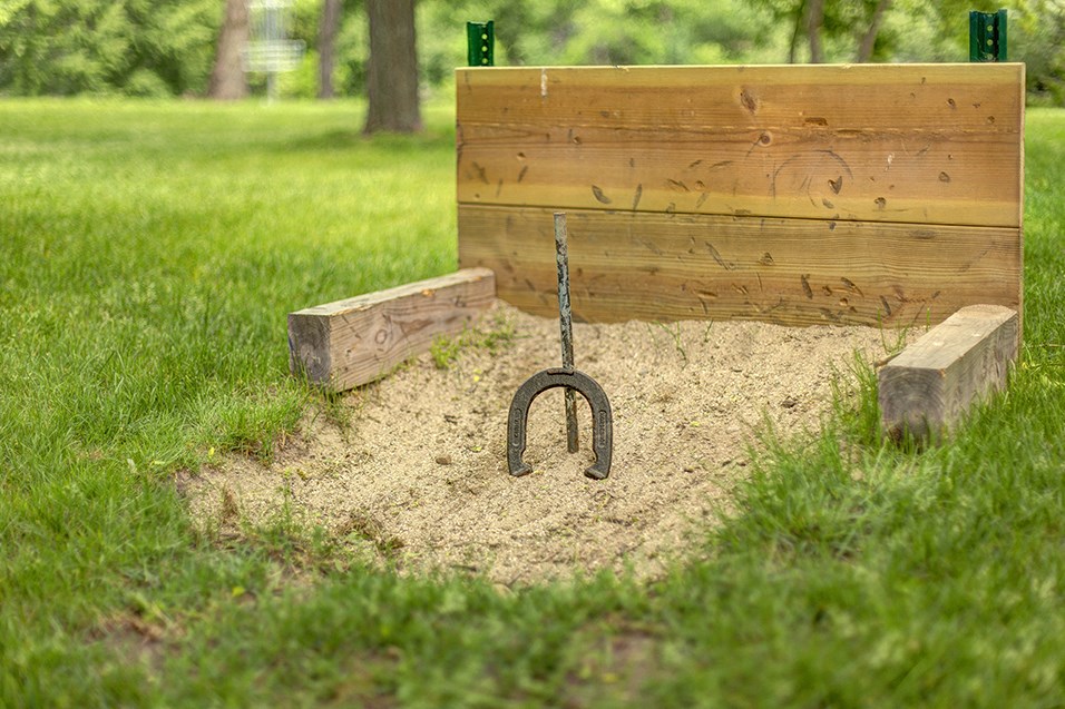 a horseshoe hangs from the ground in front of a wooden bench