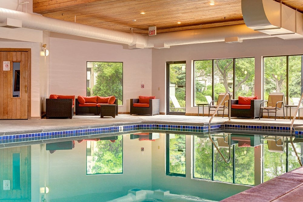 a swimming pool with furniture and chairs next to a door