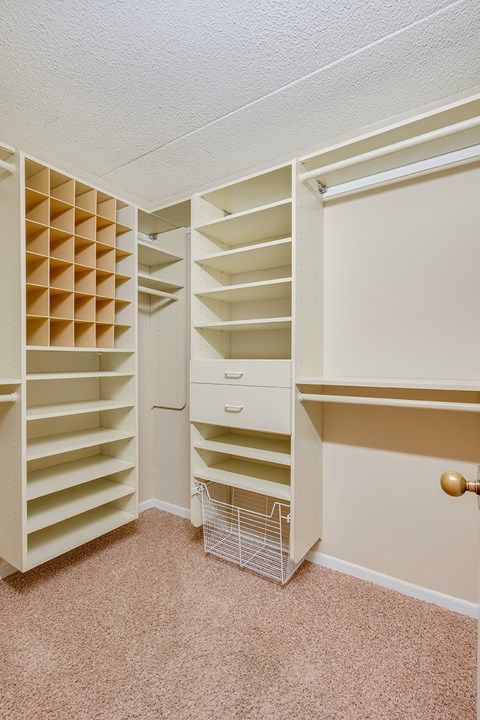 a walk in closet with shelves and a basket