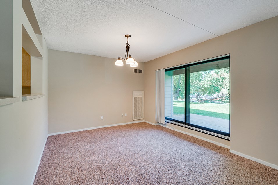 an empty living room with a large window and carpet
