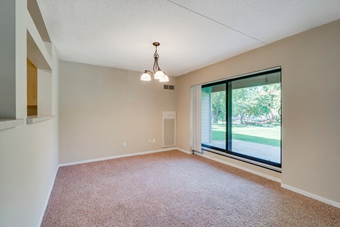 an empty living room with a large window and carpet