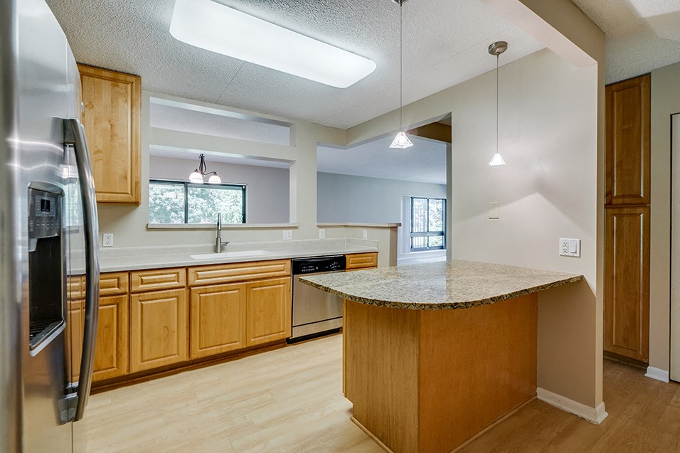 an open kitchen with an island and a stainless steel refrigerator
