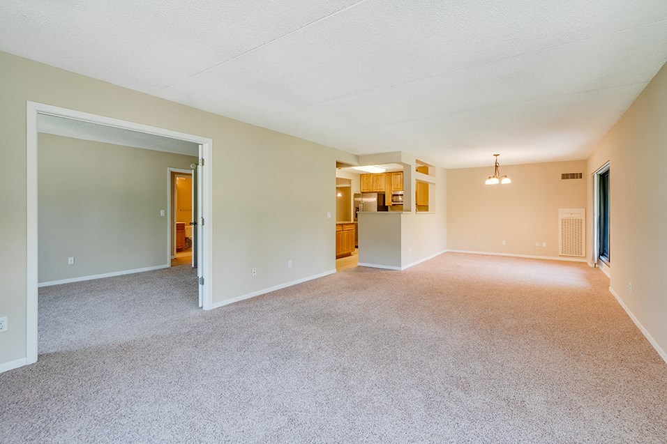 the living room and kitchen of an empty house with a carpeted floor