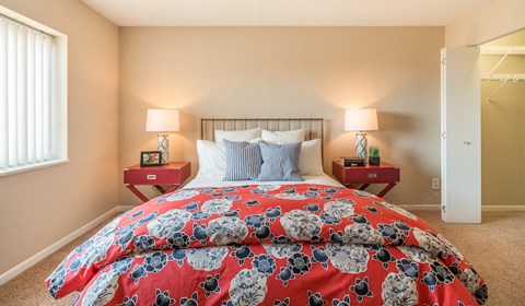 a bedroom with a bed with a red comforter