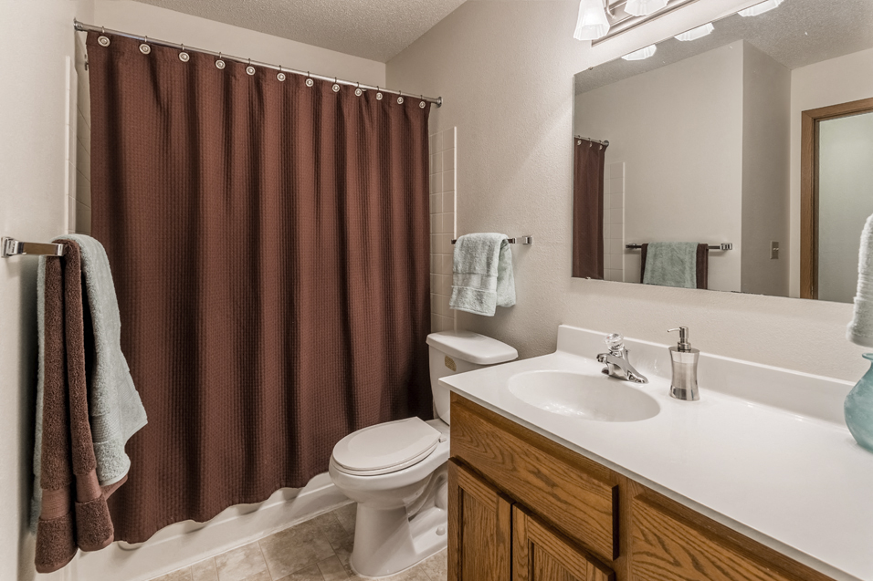 Bathroom with white countertop and brown shower curtain