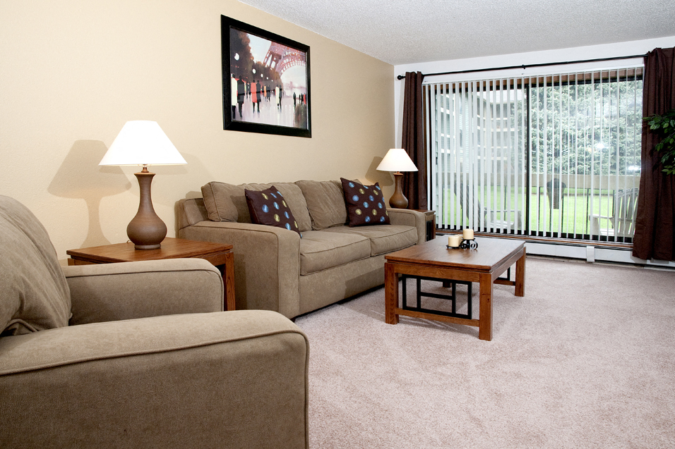 Living room with couch, chair, coffee table, and a view of a patio