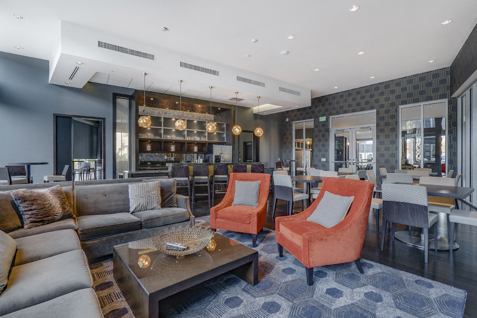 Community room with L sofa, orange chairs, coffee table, and a variety of other furniture in the background