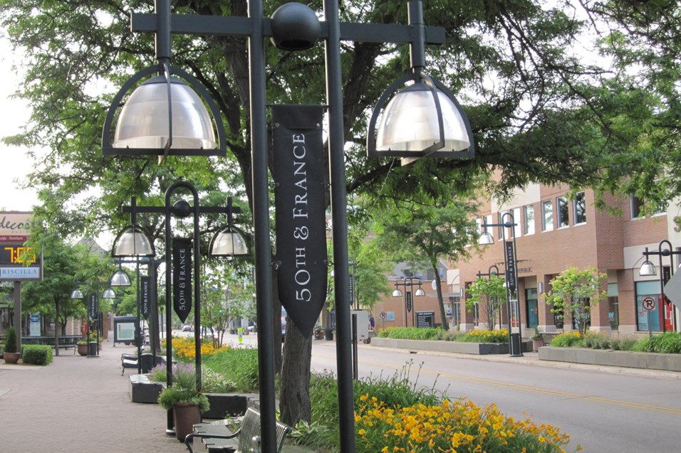a city street with street lamps and flowers on a sidewalk