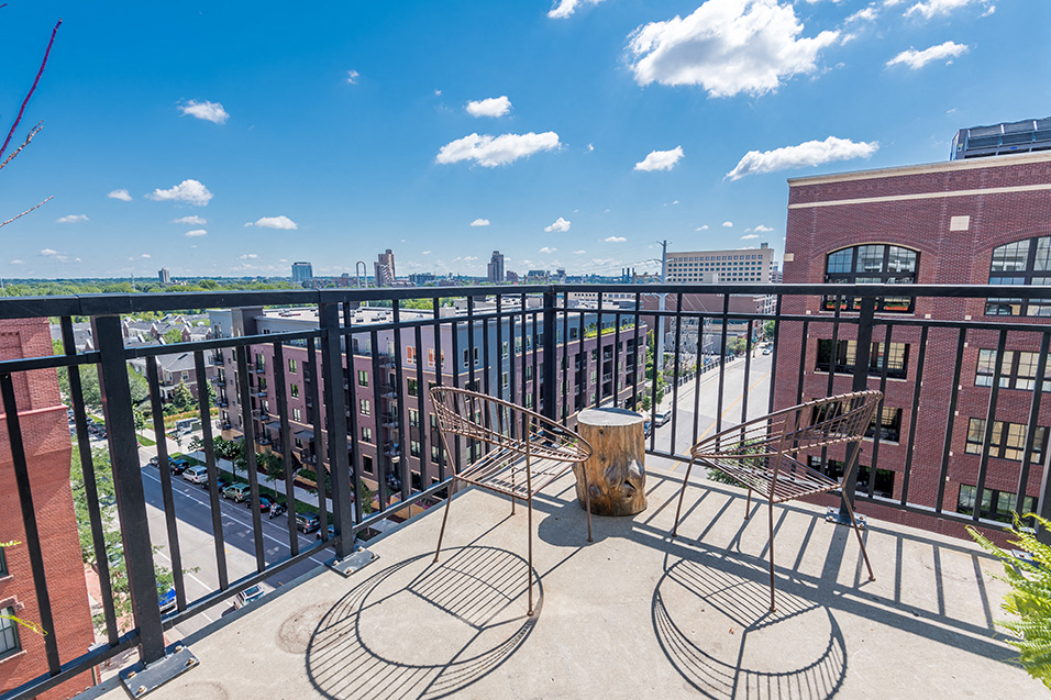 balcony with a view of downtown on a sky-blue day with two wire metal chairs
