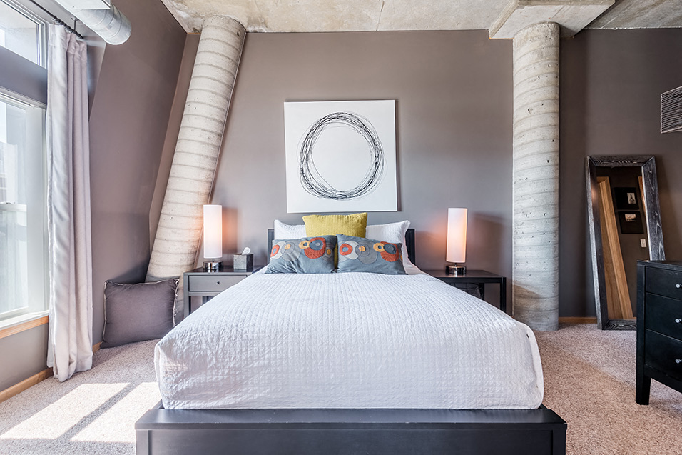 bedroom with low-sitting bed, nightstands with lamps, and circular artwork above the bed