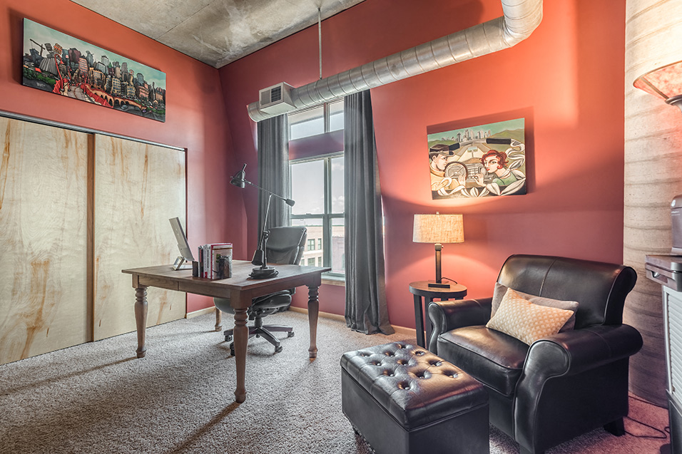 office with red walls, interesting artwork, a computer desk, and a leather recliner