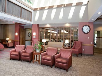 Lobby with rows of red chairs and a sofa - Photo Gallery 13