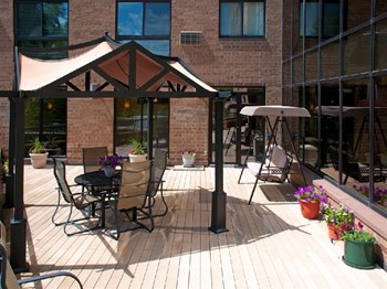 Outdoor patio with rocking bench, circle table, and various shade awnings - Photo Gallery 3