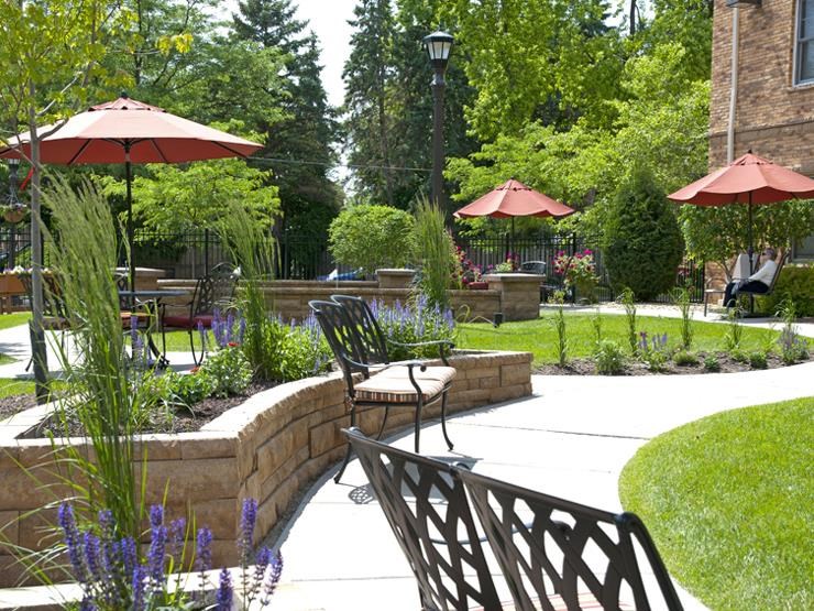a patio with chairs and umbrellas in a garden