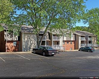 an apartment building with cars parked in a parking lot