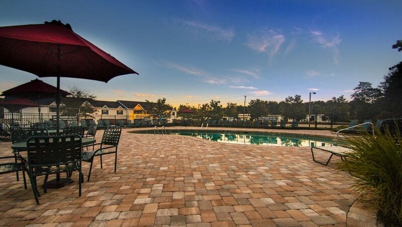 a pool and patio with chairs and an umbrella