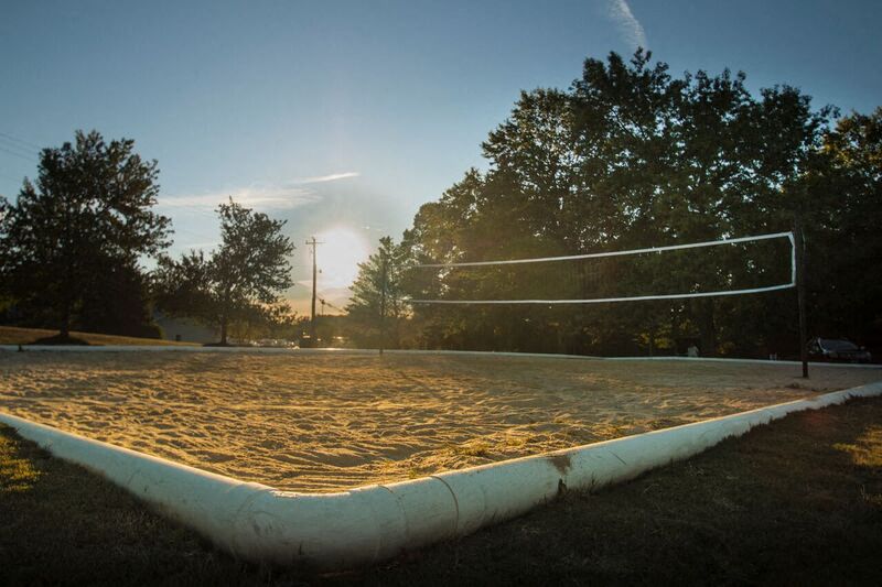 a volleyball court with the sun shining on the dirt