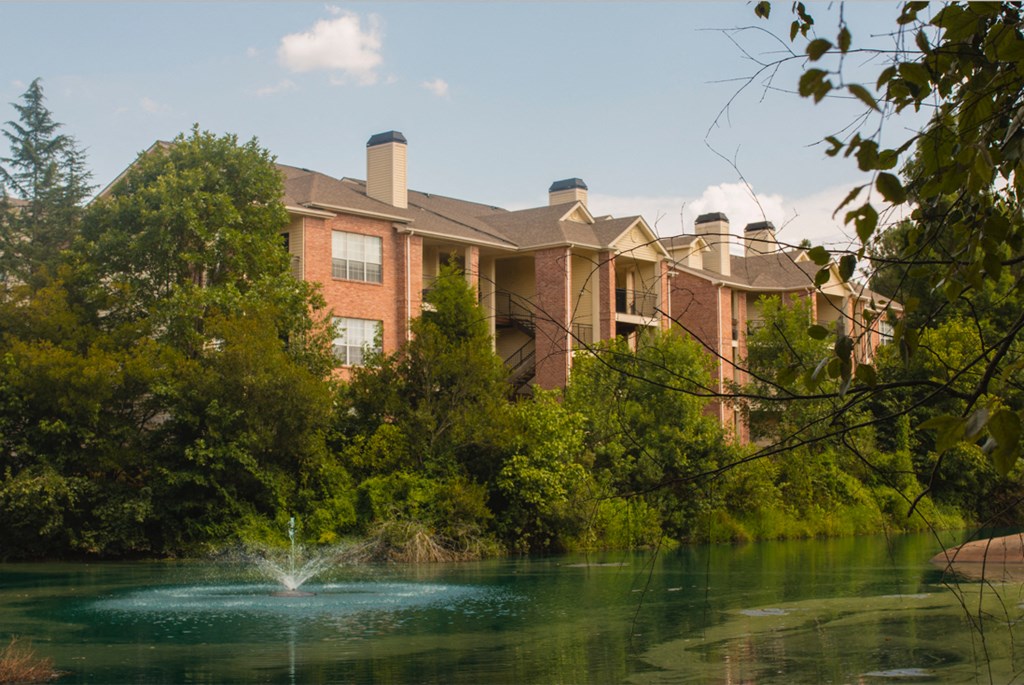 a fountain in a pond in front of a building