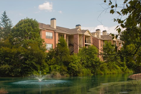a fountain in a pond in front of a building