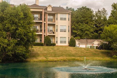 a fountain in the water in front of a large house