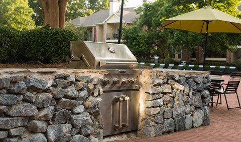 an outdoor kitchen with a grill and a stone wall