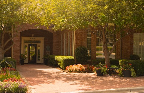the front of a building with flowers and trees