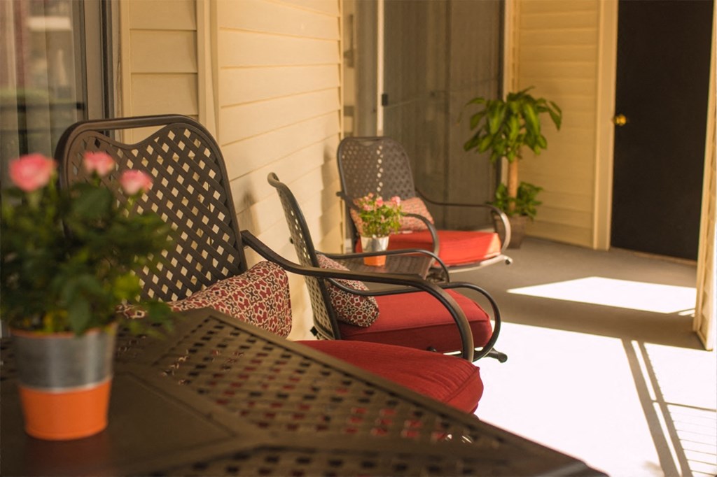 a porch with chairs and a table with flowers on it