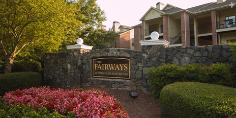 a stone wall with a sign for the apartments in front of a building