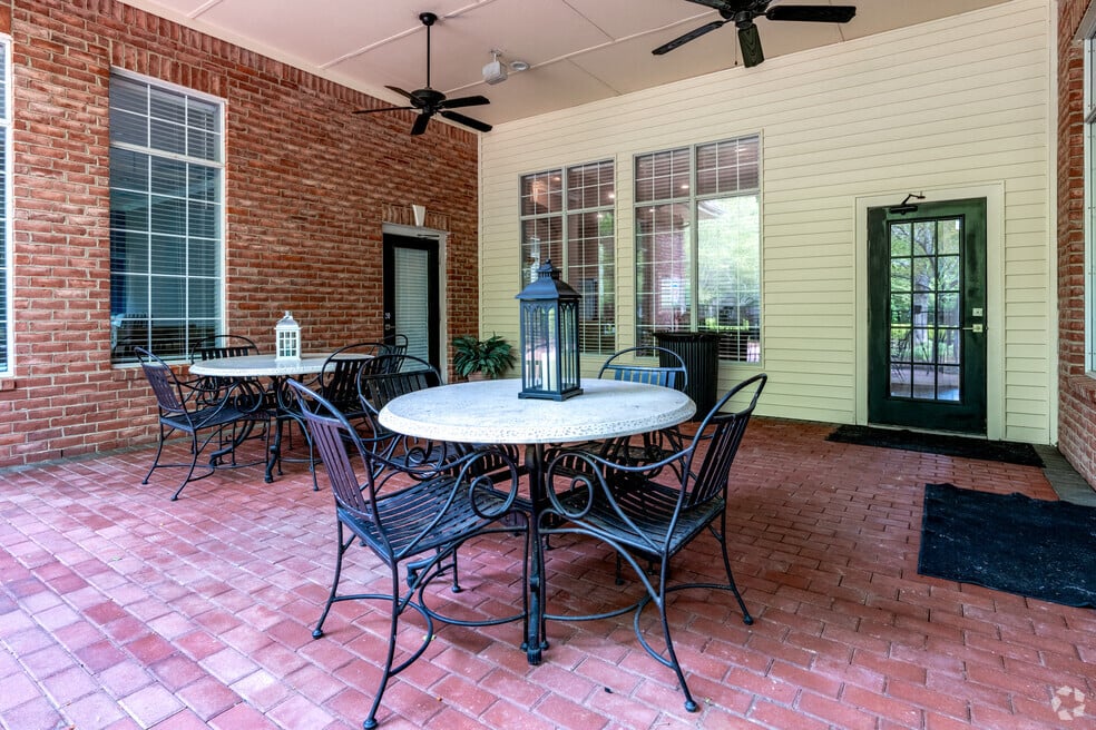 a patio with tables and chairs and a brick house