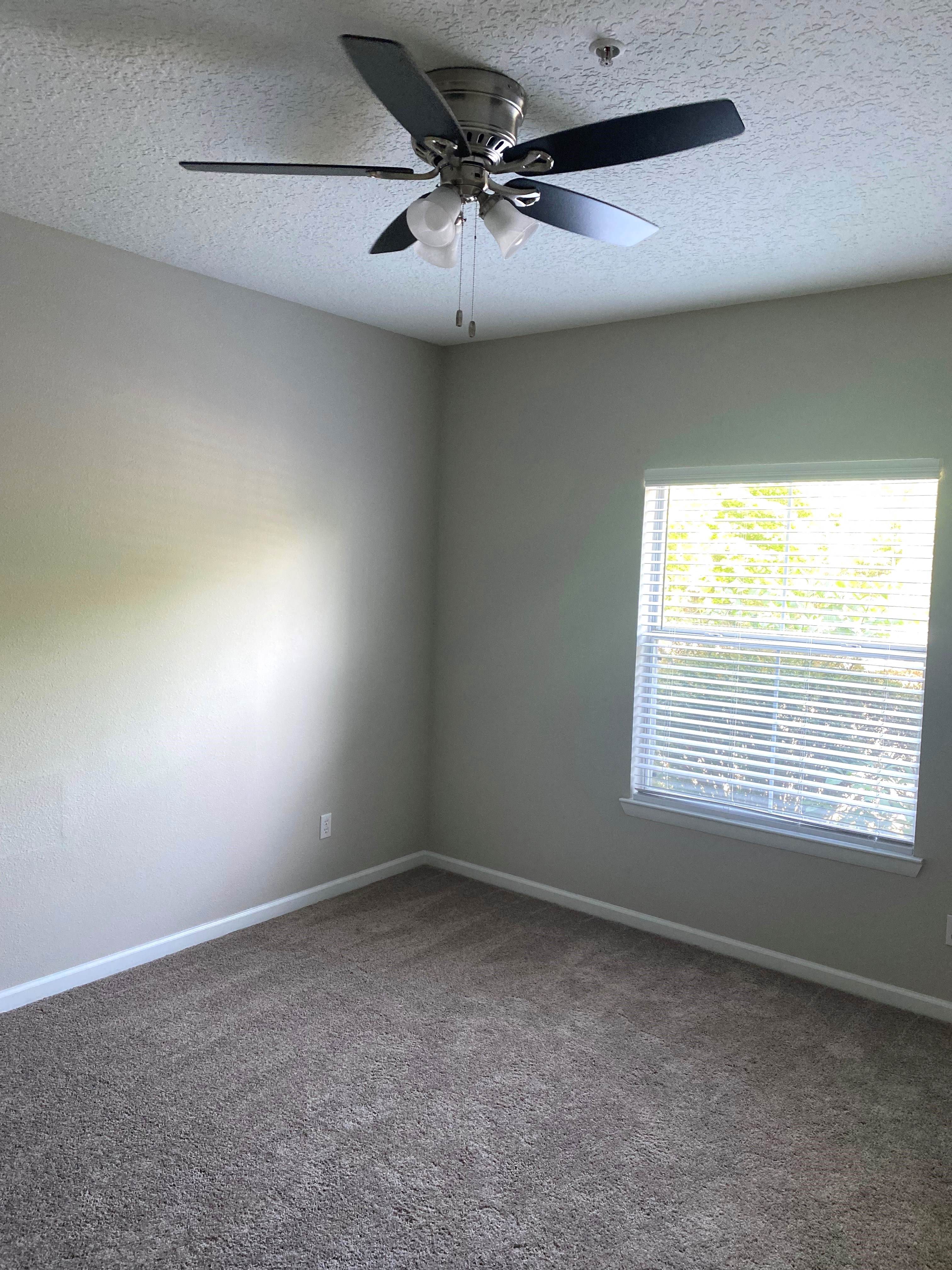 a bedroom with a ceiling fan and a window