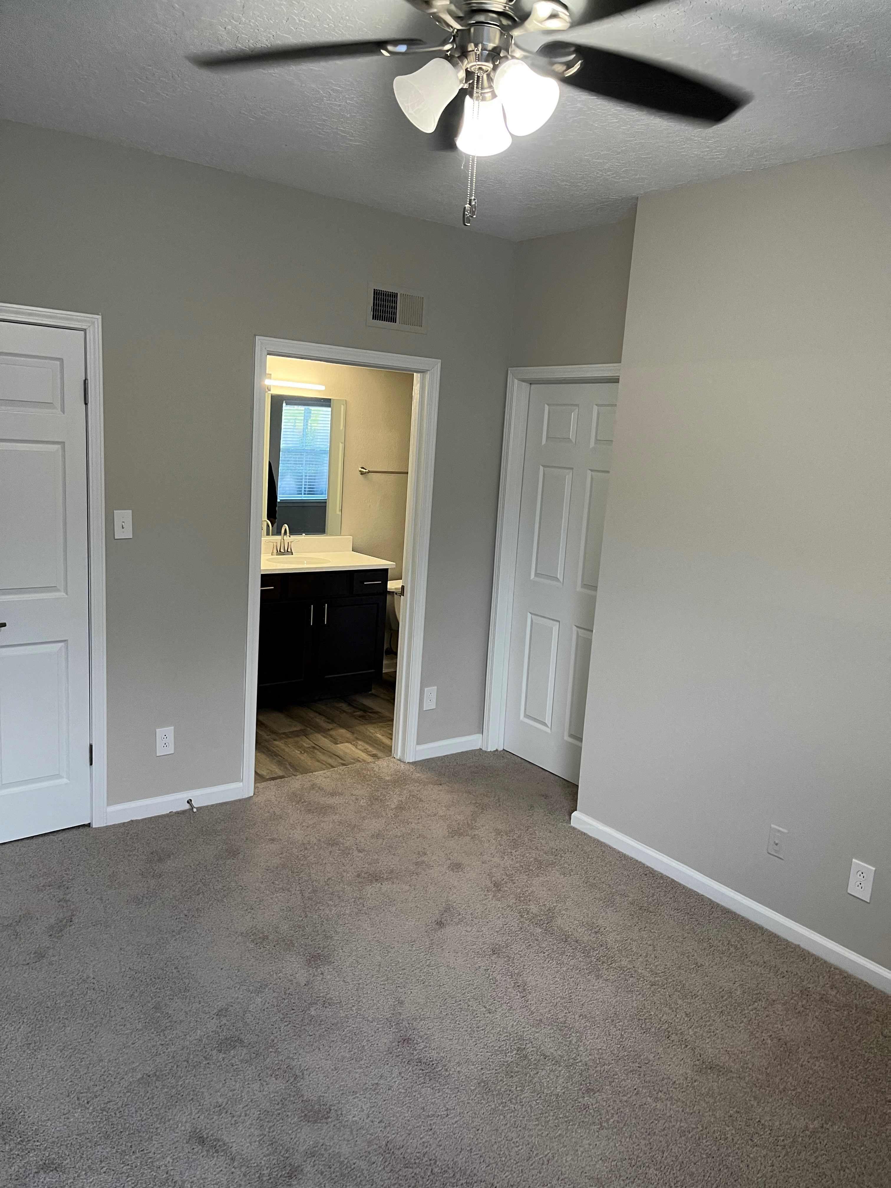 a room with a carpeted floor and a ceiling fan