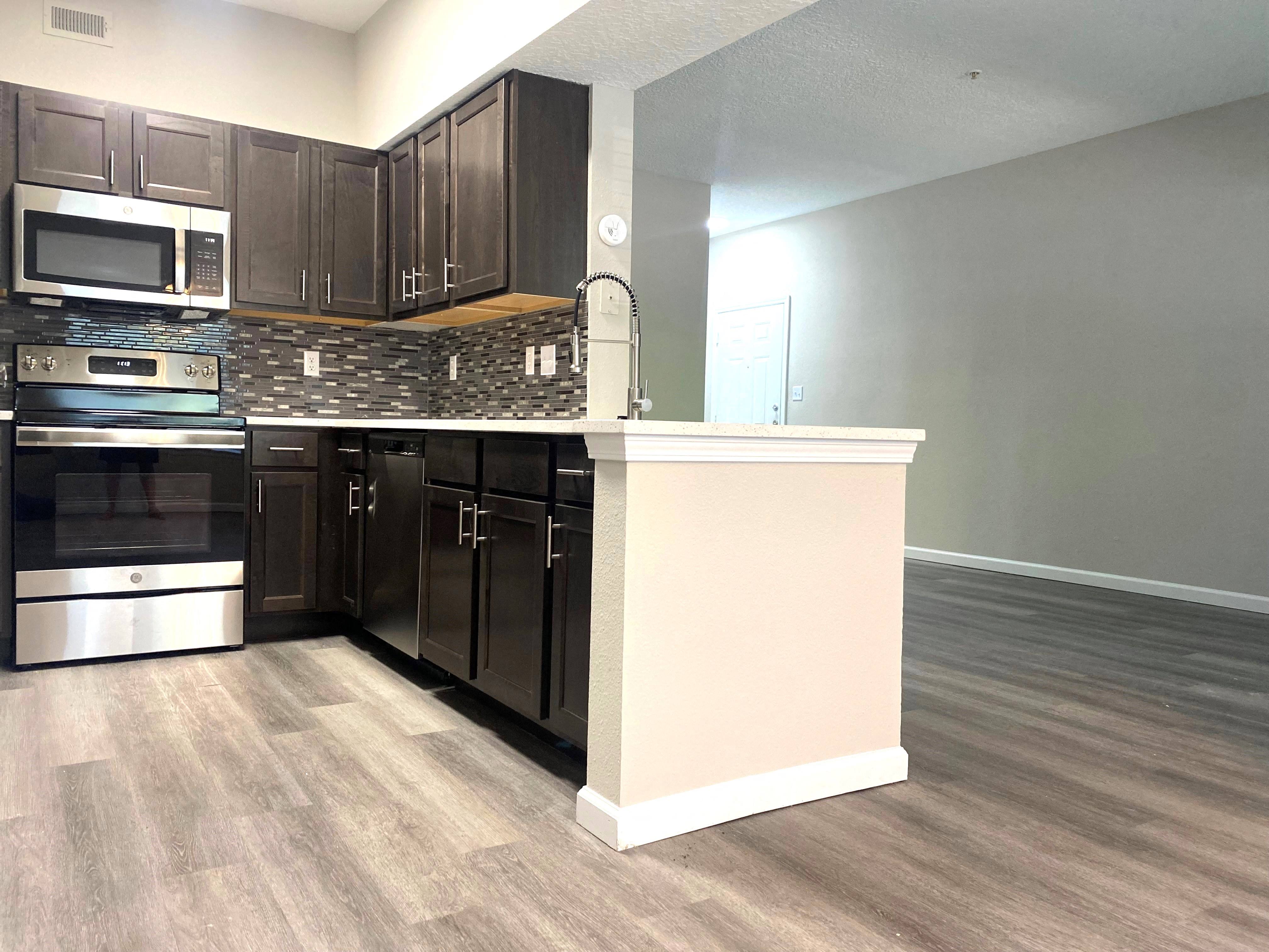 an empty kitchen with dark wood cabinets and stainless steel appliances