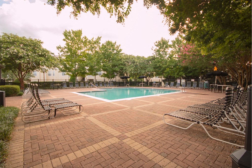 a swimming pool with chaise lounge chairs and trees