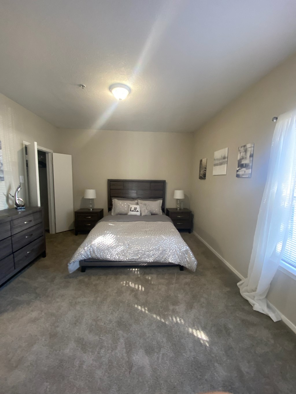 a bedroom with a bed and two dressers and a window