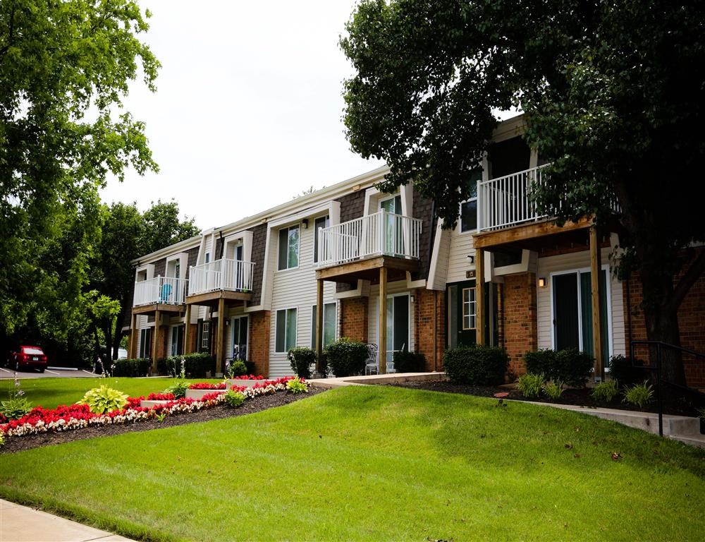 an apartment building with a lawn and flower beds
