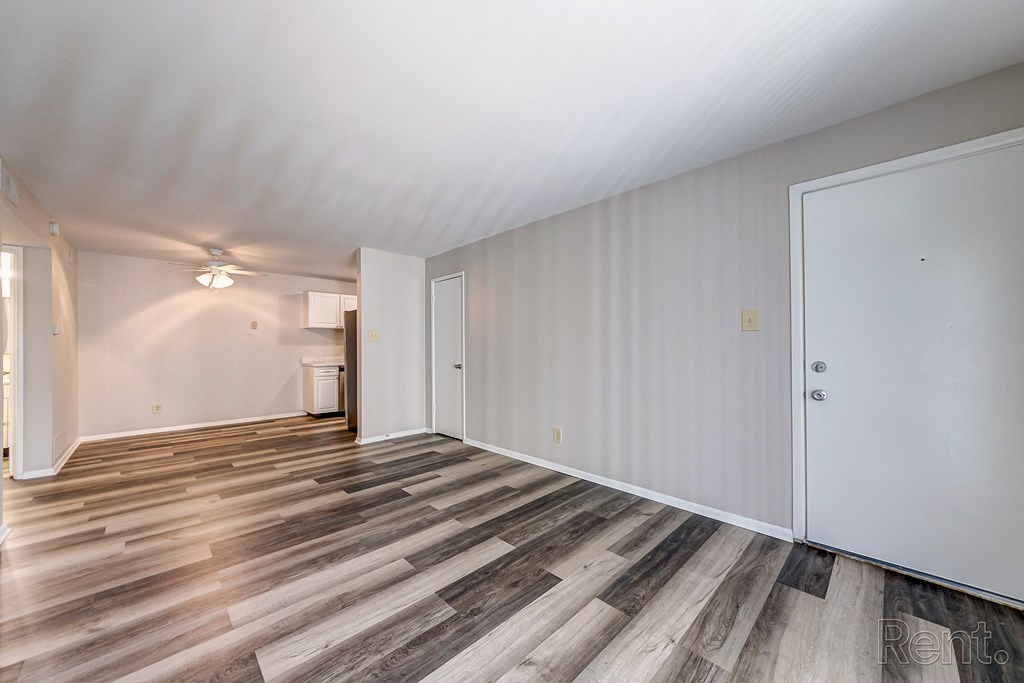 a living room with wood flooring and a door to a kitchen