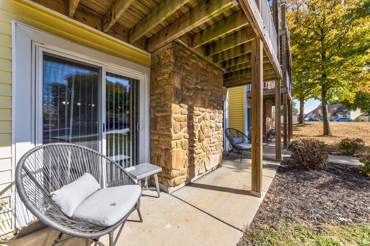 the front porch of a house with a chair and a porch swing