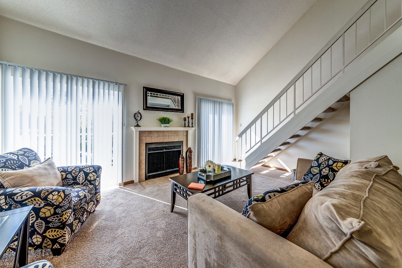 a living room with couches and a fireplace and a staircase