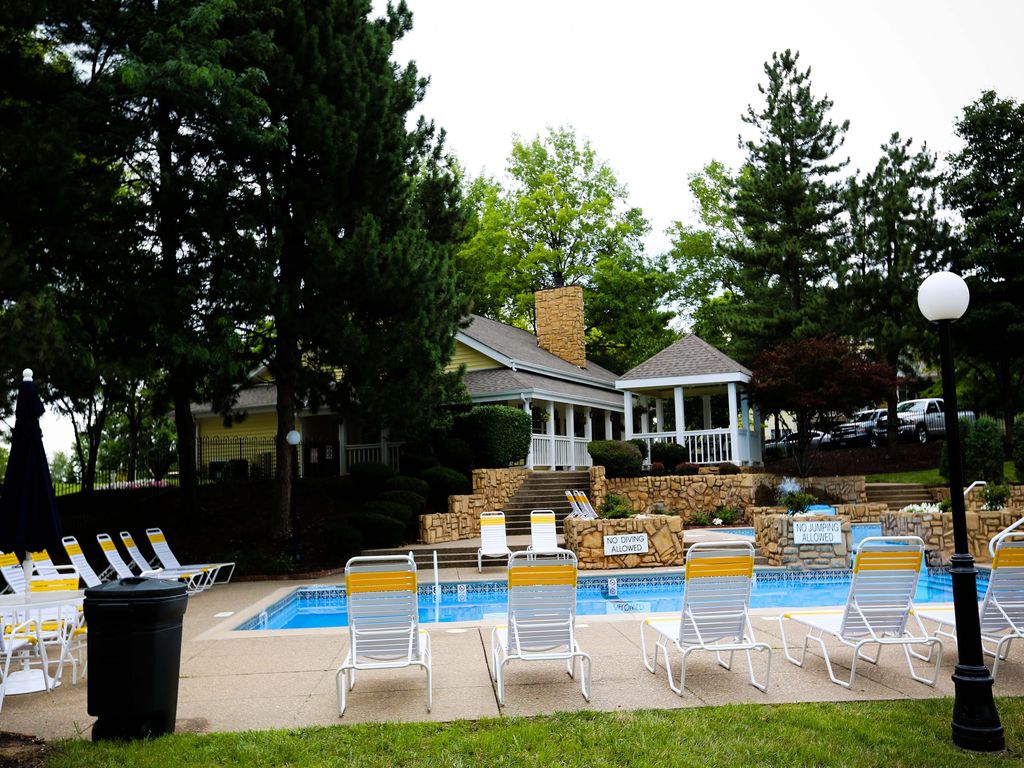 a swimming pool with chairs around it in front of a house