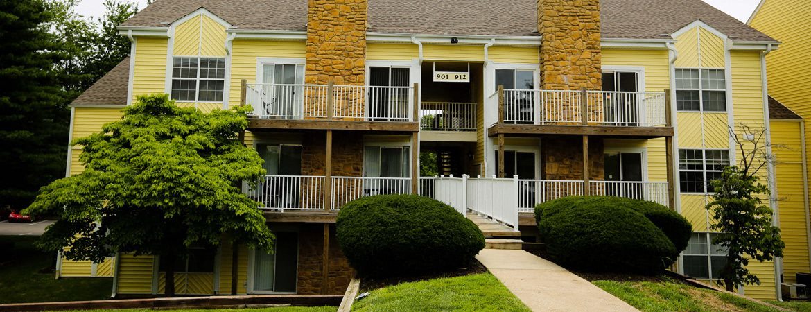 a yellow house with balconies and a sidewalk